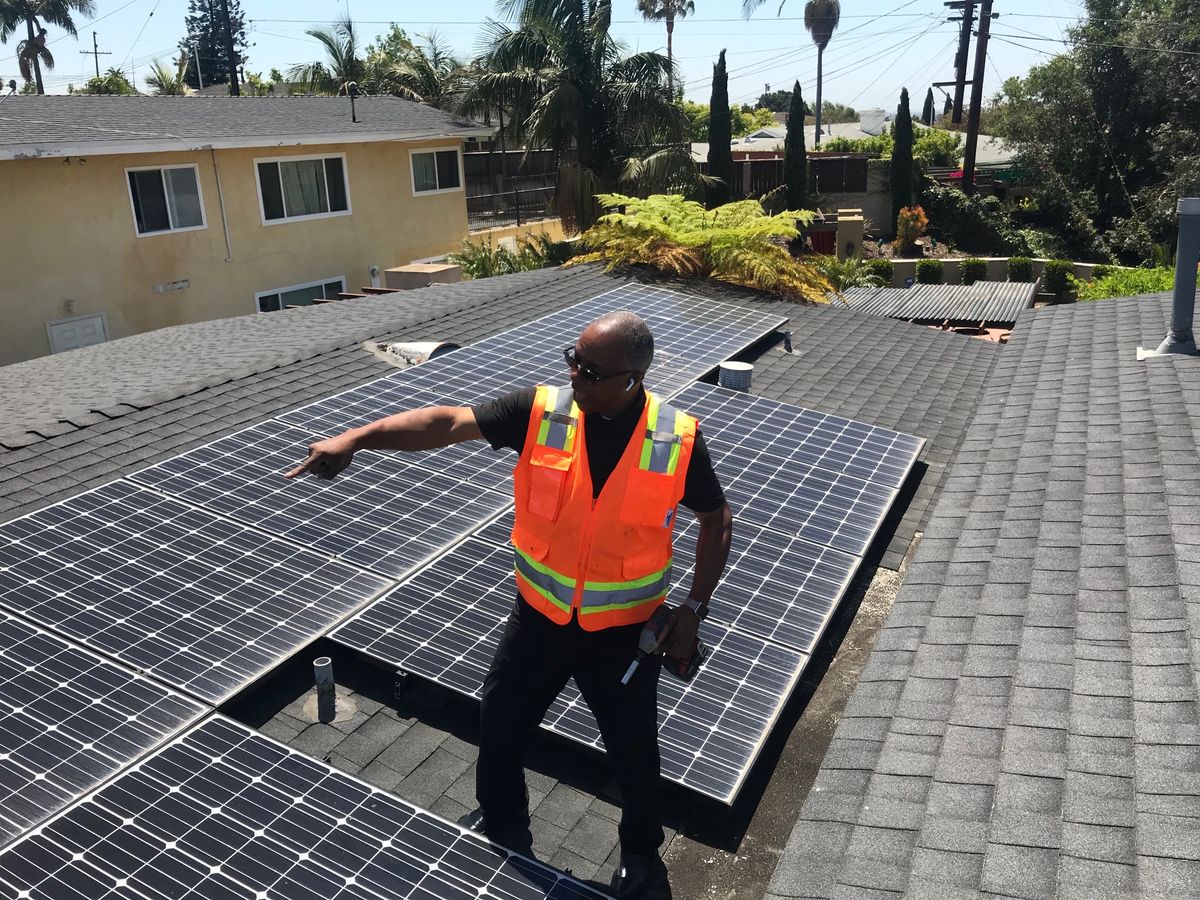 Alfred Scaife on a residential roof in a safety vest, checking a newly laid array