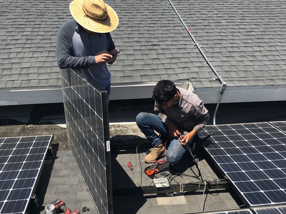 Two installers wiring a panel into an array mid-installation